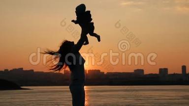 一位年轻的母亲高兴地把她的小儿子扔了上来。 日落时分，母亲和孩子在河边散步，玩得很开心。